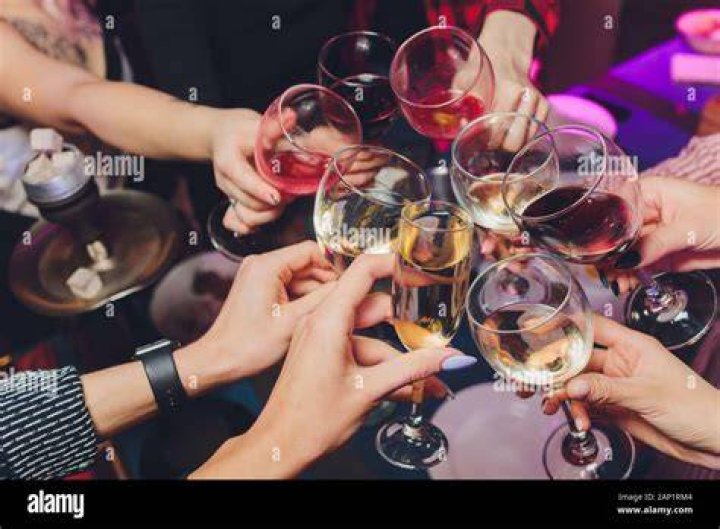 People clinking glasses in wine taste as they celebrate a birthday party in backyard People clinking glasses in wine taste as they celebrate a birthday party in backyard