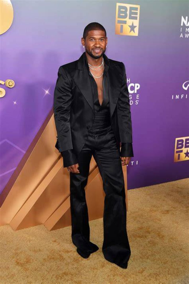 Usher Raymond wears black suit and bowtie, smiles next to girlfriend Jennifer Goicoechea.
